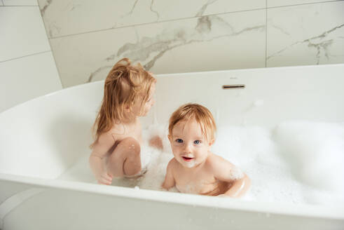 Kleiner Bruder und kleine Schwester baden in einem Schaumbad - CAVF75515