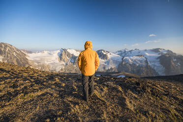 Rückansicht eines Wanderers mit gelber Jacke auf einem Berggipfel. - CAVF75533