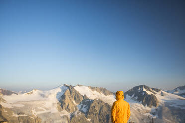 Hiker looking at view of glaciated mountains in Canada. - CAVF75534