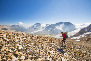 Side view of backpacker hiking over rocky terrain. - CAVF75537