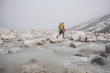 Wanderer überquert den Fluss mit Hilfe von Felsbrocken. - CAVF75539