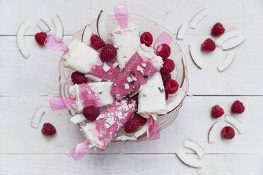 Homemade coconut and raspberry popsicles in glass bowl - GWF06472