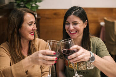 Freunde stoßen mit einem Glas Rotwein in einem Restaurant an - GRCF00180
