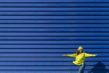 Tanzen Teenager-Mädchen hören Musik mit Kopfhörern vor blauem Hintergrund - ERRF02681