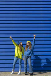 Two teenage girls wearing matching clothes in front of blue background - ERRF02694