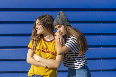 Portrait of two teenage girls in front of blue background - ERRF02702