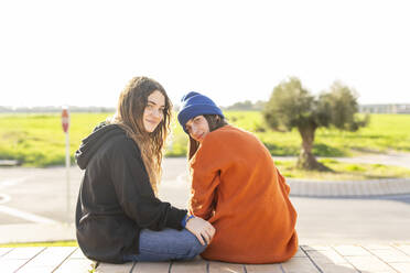 Portrait of two teenage girls sitting outdoors - ERRF02720