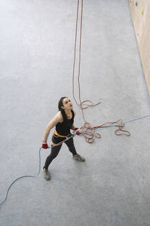 Frau mit einem Seil, das einen Partner an der Wand in einer Kletterhalle sichert - AHSF01918