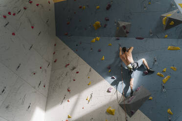 Mann ohne Hemd klettert in einer Kletterhalle an der Wand - AHSF01950