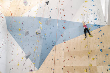 Frau klettert in einer Kletterhalle an der Wand - AHSF01960