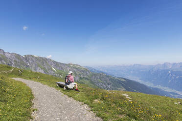 Switzerland, St Gallen Canton, Glarus Alps, Man taking a break on the Panoramic hiking trail in the Tectonic Arena Sardona - GWF06475