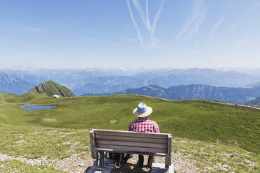 Schweiz, Kanton St. Gallen, Mann ruht sich auf Bank aus und schaut auf die Berge - GWF06487