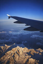 Frankreich, Auvergne-Rhone-Alpes, Flügel eines Airbus A321 im Flug über die europäischen Alpen und den Genfer See in der Morgendämmerung - RORF02013