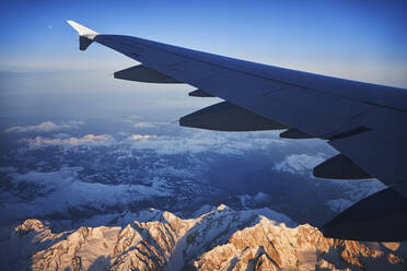 Frankreich, Auvergne-Rhone-Alpes, Flügel eines Airbus A321 im Flug über die europäischen Alpen und den Genfer See in der Morgendämmerung - RORF02014