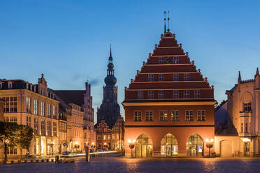 Deutschland, Mecklenburg-Vorpommern, Greifswald, Beleuchtetes Rathaus in der Abenddämmerung mit Turm von St. Nikolai im Hintergrund - WDF05831