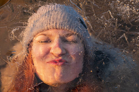 Porträt eines Teenagers, der hinter einer eisbedeckten Fläche ein lustiges Gesicht zieht, lizenzfreies Stockfoto