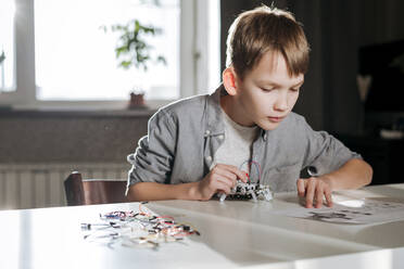 Boy making robot up with instruction at home - EYAF00940