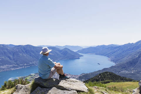 Hiker at Cimetta mountain top looking towards Lago Maggiore and Ascona, Locarno, Ticino, Switzerland stock photo