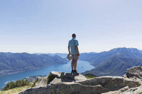 Hiker at Cimetta mountain top looking towards Lago Maggiore and Ascona, Locarno, Ticino, Switzerland stock photo