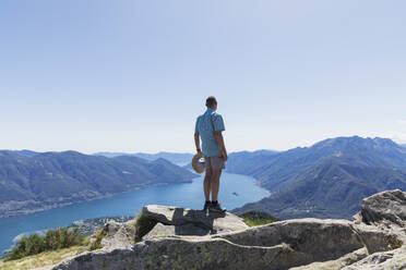 Hiker at Cimetta mountain top looking towards Lago Maggiore and Ascona, Locarno, Ticino, Switzerland - GWF06500