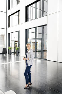 Erfolgreiche Geschäftsfrau steht in der Eingangshalle eines Bürogebäudes - PESF01862