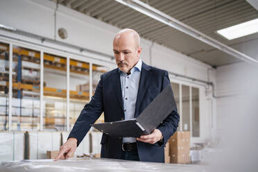 Businessman holding a folder in a factory - DIGF09313