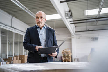 Businessman holding a folder in a factory - DIGF09314