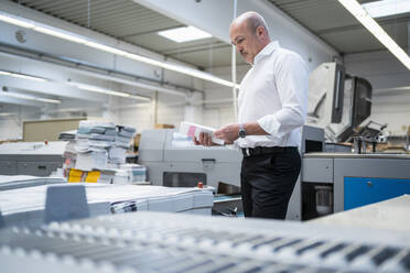 Geschäftsmann in einer Druckerei bei der Produktkontrolle - DIGF09326