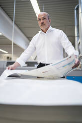 Businessman in a printing plant holding paper - DIGF09329