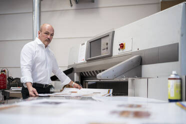 Geschäftsmann in einer Druckerei bei der Produktkontrolle - DIGF09338