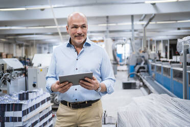 Portrait of a confident businessman in a factory holding tablet - DIGF09349