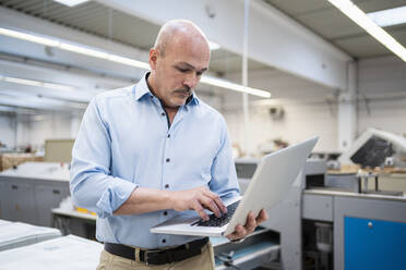 Geschäftsmann mit Laptop in einer Fabrik - DIGF09355