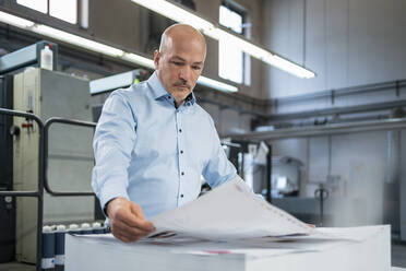 Geschäftsmann in einer Druckerei bei der Produktkontrolle - DIGF09364