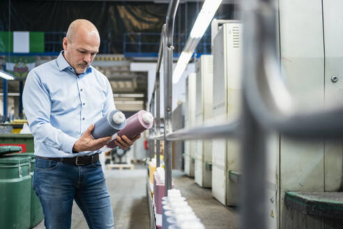 Businessman holding toner in a printing plant - DIGF09369