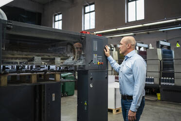 Geschäftsmann schaut sich eine Maschine in einer Fabrik an - DIGF09374