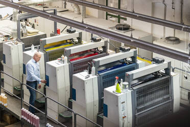 Geschäftsmann an Maschinen in einer Druckerei stehend - DIGF09390