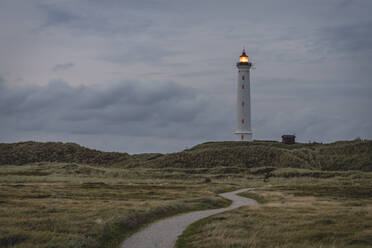 Denmark, Hvide Sande, Footpath toward coastal lighthouse at dusk - KEBF01463