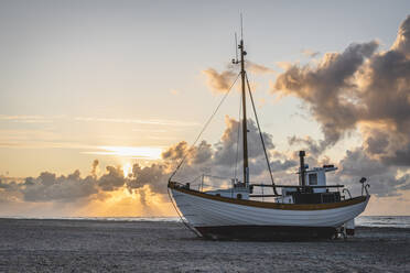 Dänemark, Slettestrand, Fischerboot links am sandigen Küstenstrand bei Sonnenuntergang - KEBF01467