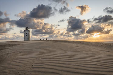 Denmark, Lonstrup, Clouds over rippled sand dunes and Rubjerg Knude Lighthouse at sunset - KEBF01471