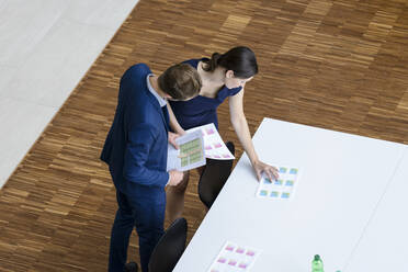 Businessman and woman preparing boardroom for a meeting, elevated view - BMOF00207