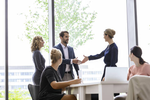 Businesswoman greeting colleagues in her team stock photo