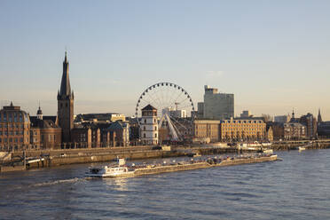 Germany, North Rhine-Westphalia, Dusseldorf, Container ship passing Saint Lambertus Church and coastal Ferris wheel - WIF04194