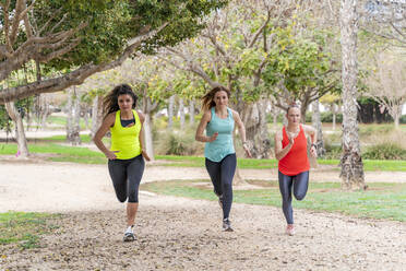 Three sporty young women running in a park - DLTSF00576