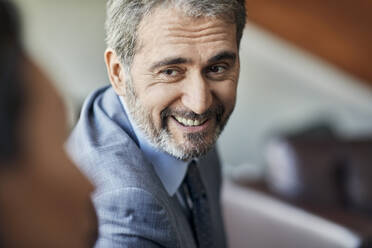 Porträt eines lächelnden Geschäftsmannes mit Blick auf einen Kollegen - ZEDF02988