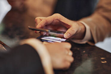 Close-up of man paying contactless with credit card at counter - ZEDF02991