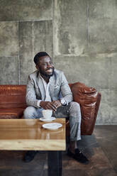 Smiling businessman relaxing in hotel lobby - ZEDF03034