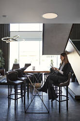 Businesswoman using tablet in hotel lobby - ZEDF03056