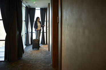 Geschäftsfrau im Hotelkorridor mit Rollkoffer - ZEDF03106