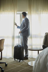 Geschäftsmann im Hotelzimmer schaut aus dem Fenster - ZEDF03125