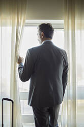 Geschäftsmann im Hotelzimmer schaut aus dem Fenster - ZEDF03126